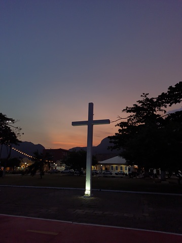 a white cross with an orange sunset in the background