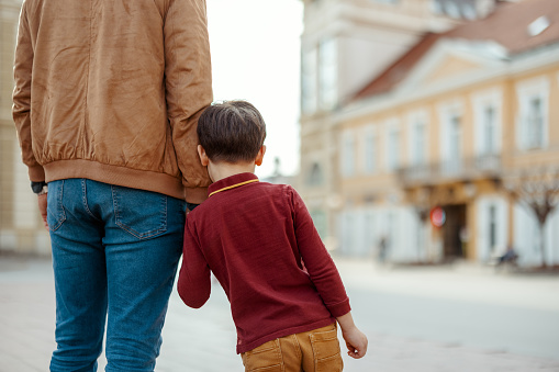 Son Holding His Faceless Father Hand While Walking Outdoors in the City Center