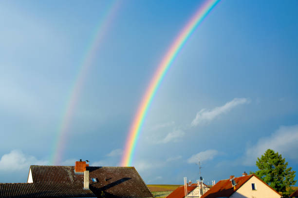 Rainbow over the house after a storm with clouds in the city. Panoramic view of beautiful sunset.