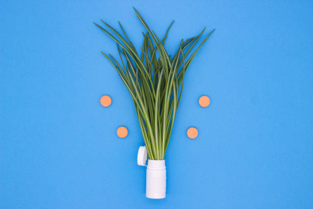 Lively green grass sprouting from a tube with orange tablets on blue.