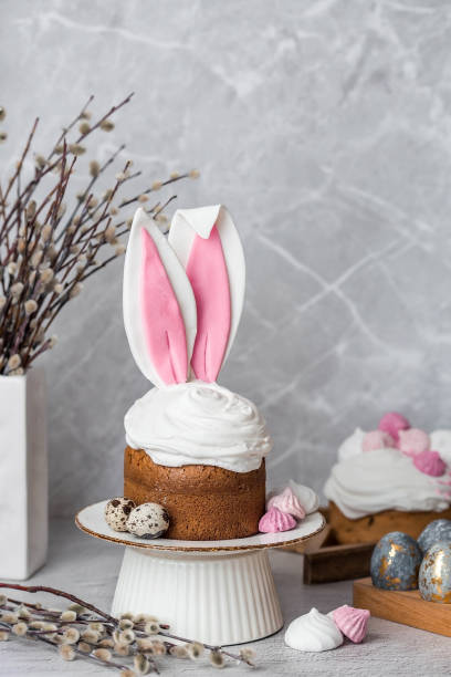 istock Beautiful stylish still life. Easter cake with rabbit (hare) ears, meringue, marshmallows, Easter eggs and willow branches and on a light concrete background. Happy Easter 2024. 2091824073