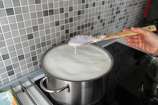 Boiling milk in saucepan in modern kitchen.