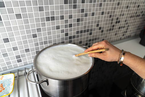 Boiling milk in saucepan in modern kitchen.