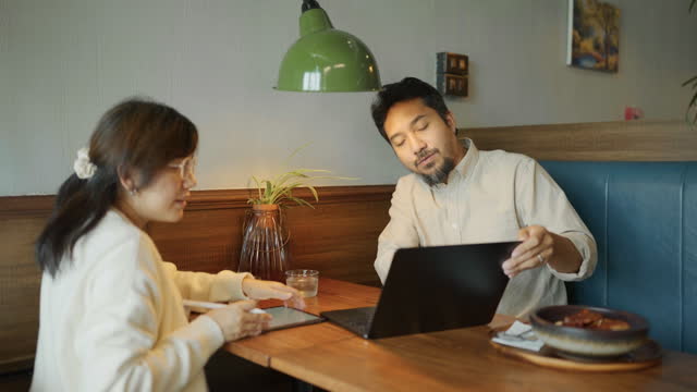 Asian men and women work together on their lunch break in a restaurant near their office.