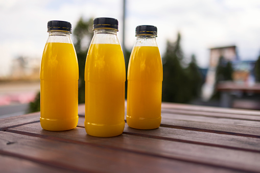 plastic bottles with orange juice on the wooden table