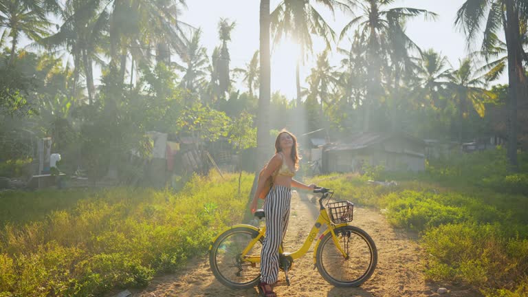 Cheerful woman riding bicycle through coconut grove  on Gili Trawangan