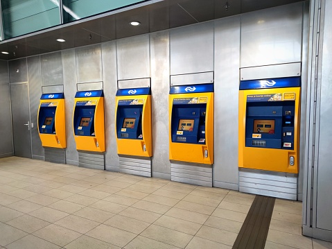 Utrecht, Netherlands - February 2024: Yellow-blue colored pay machines where you can buy train tickets at the train station of Utrecht, The Netherlands.