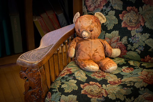 A brown teddy bear on a bed.