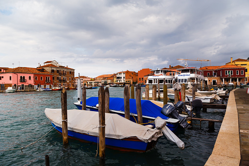 Murano, Italy - October, 6 2019: Typical street on Murano island in Venice, wharf for gondolas and boats, glass blowing factories and Murano Lighthouse or Faro di Murano.