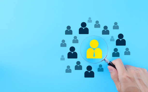 istock HR, human resources management technology concept. Targeted individual selection. A magnifying glass focusing on a highlighted individual among silhouetted figures against a blue background. CRM, 2091968846
