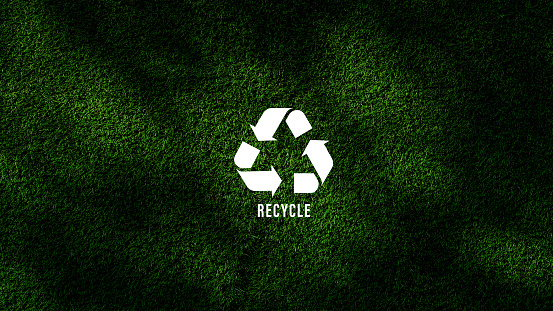 Reduce, reuse, recycle symbol with green grass background, ecological metaphor for ecological waste management and sustainable and economical lifestyle.