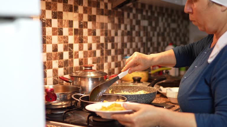 Preparation for iftar, woman puts food from the stove onto plates