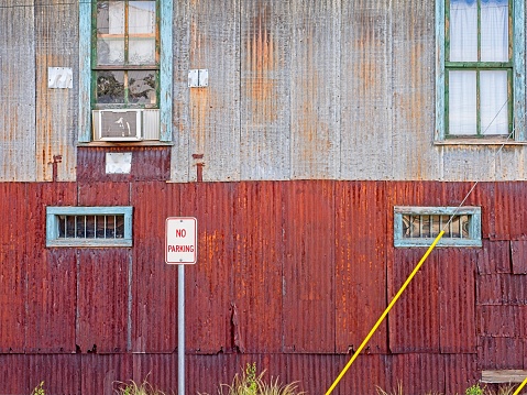 The rustic detail of a rural barn in Texas behind a No Parking sign. Rural American no parking and rusty siding.