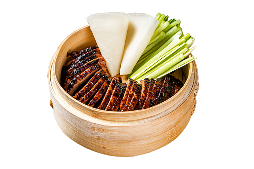 Peking Duck in bamboo steamer served with cucumber, green onion, and wheaten chinese pancakes. Isolated on white background. Top view