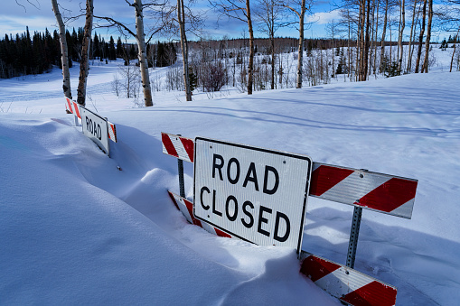 Road Closed Sign with Snow in Winter - Closure in backcountry along mountain road at elevation. Winter closure due to large amounts of fresh snow.