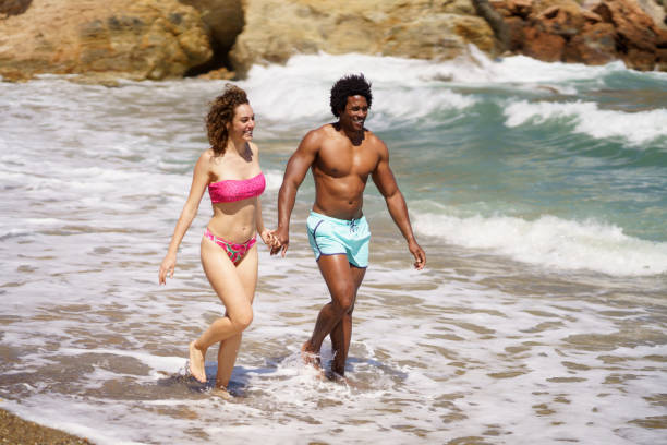 istock Happy diverse man and woman walking on wet coast 2092068551