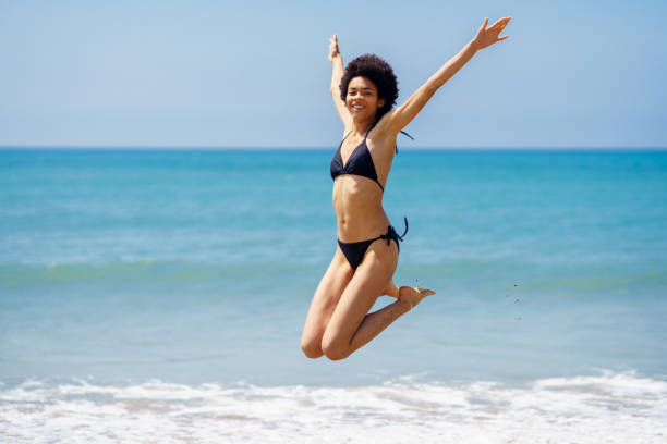 istock Active woman in bikini jumping near sea 2092072728