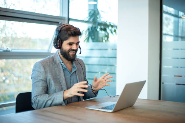istock Friendly businessman using a headset and laptop in a modern office. 2092106303