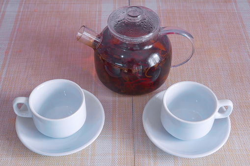 Glass transparent teapot with black tea and two empty white cups on the table. Tea concept.
