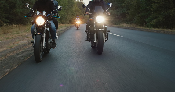 A group of bikers drives along the highway, in the frame you can see the wheels and headlights.