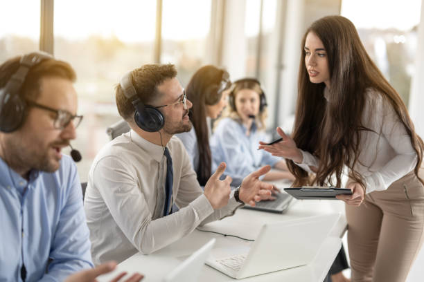 istock Attractive businesswoman supervisor training work to her multi-ethnic colleagues in call center office. 2092166857