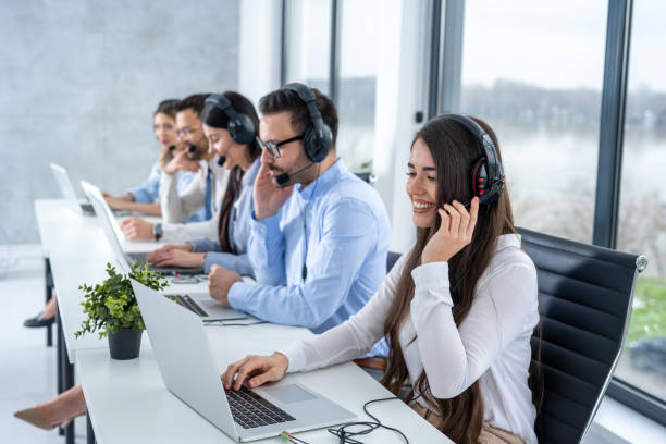 istock Group of call center workers with headsets using laptops in office. 2092174238