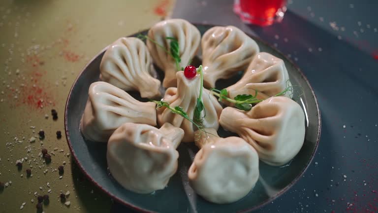 closeup of georgian khinkali with meat on dark plate on grey background