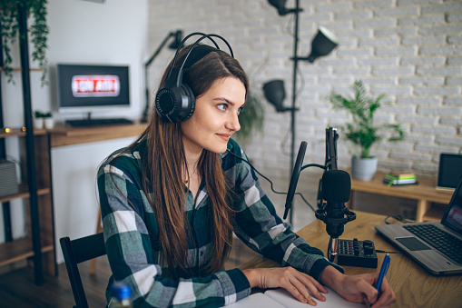Female radio presenter recording a podcast in a domestic looking sound studio