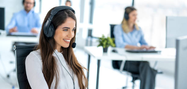 istock Smiling service desk analyst with headset answering client's questions and resolving client's issues in call center. 2092190554