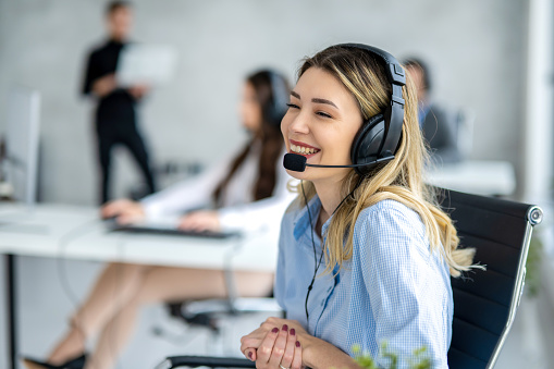 Adorable blond haired woman with headset chatting with customer at call center