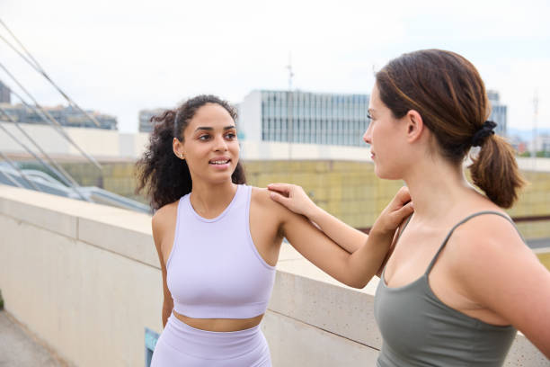 Sporty women friends doing a leg stretching exercise while exercising outdoors on a sunny day