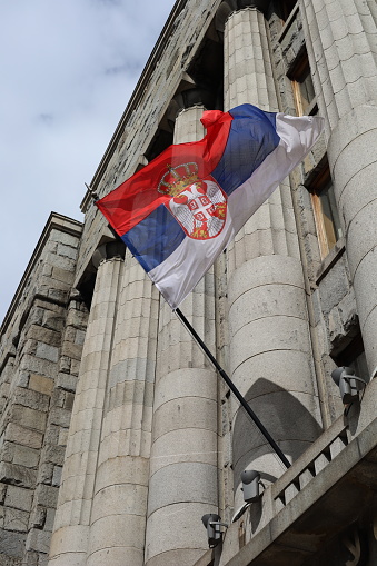 Serbian flag with a government building in the background