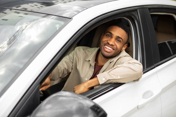 Handsome young man driving his car and smiling at the camera
