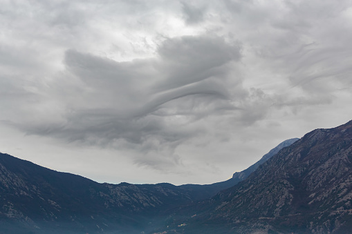 Dramatic undulating clouds hang over the mountainous landscape of Kotor Bay, signaling a change in weather