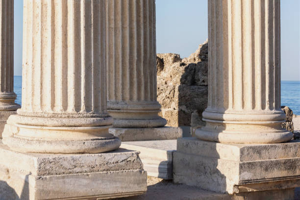 Apollo temple colonnade. Ancient columns stand in bright sunlight, blue sea in background, remnants of a historical temple. Ancient Side city, Manavgat, Turkiye (Turkey)