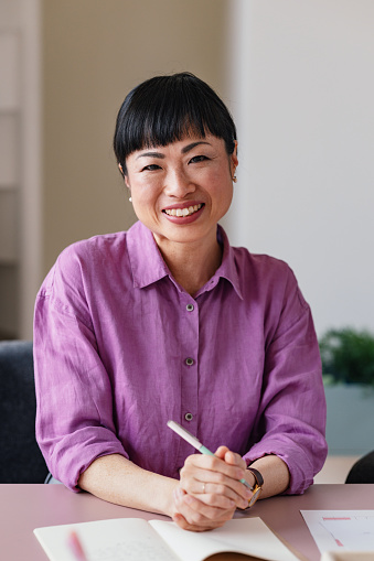 Confident Asian businesswoman smiling while working in a modern office setting.