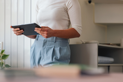 Cropped view of a businesswoman using a digital tablet in an office environment.