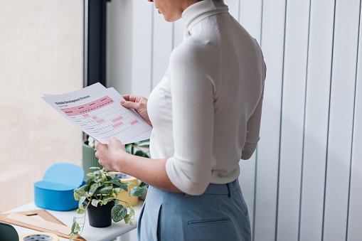 Focused businesswoman analyzing a colorful statistical document in a modern office setting.