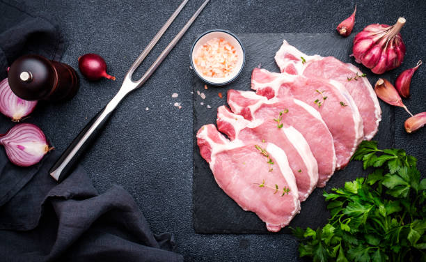 istock Raw pork chops on slate board prepared for cooking with spices and pepper. Black kitchen table background,  top view 2092417567