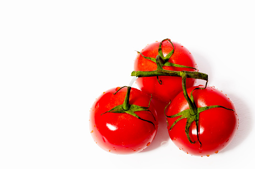 Cherry tomatoes and halves are flying close-up on a white background. Isolated