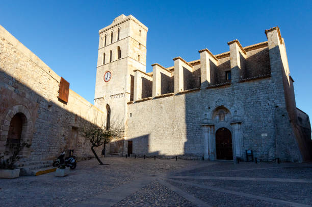 An image capturing the historic beauty of Ibiza Old Town, Dalt Vila, bathed in the warm glow of sunset. The ancient walls and charming architecture of this UNESCO World Heritage site are highlighted against the backdrop of the setting sun, showcasing the timeless elegance and Mediterranean charm of this iconic destination.
