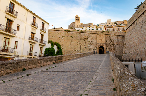 An image capturing the historic beauty of Ibiza Old Town, Dalt Vila, bathed in the warm glow of sunset. The ancient walls and charming architecture of this UNESCO World Heritage site are highlighted against the backdrop of the setting sun, showcasing the timeless elegance and Mediterranean charm of this iconic destination.