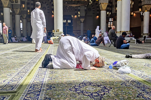 Medina, Saudi Arabia - March 10, 2023: Muslims read Quran and pray inside of Masjid Nabawi. Nabawi Mosque is the second holiest mosque in Islam and here is Prophet Muhammad is laid to rest