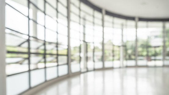 Office building lobby hall blur background or blurry school hallway corridor interior view looking toward empty corridor entrance, glass curtain wall and floor with exterior light illumination