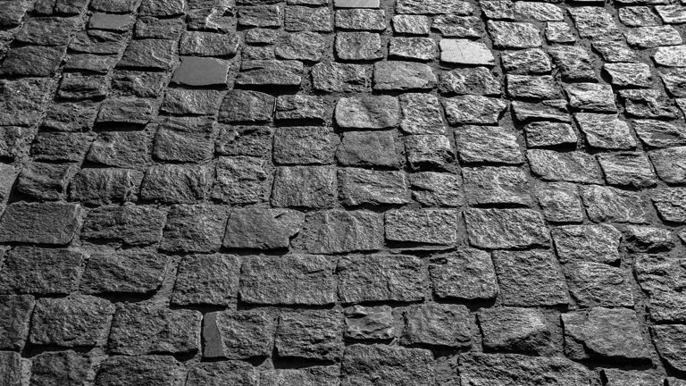 Video background of black cobbled stone road. Black or dark grey stone pavement texture. Ancient paving stone background