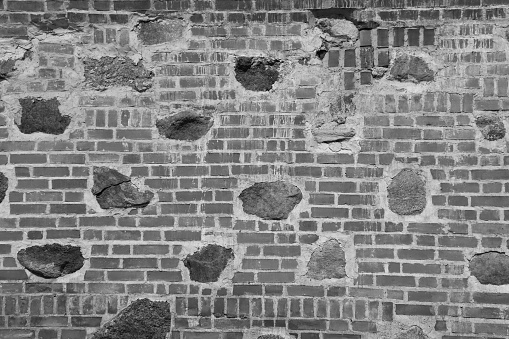 Medieval wall made of bricks and stones. Old castle wall. Abandoned brick wall damaged by time.