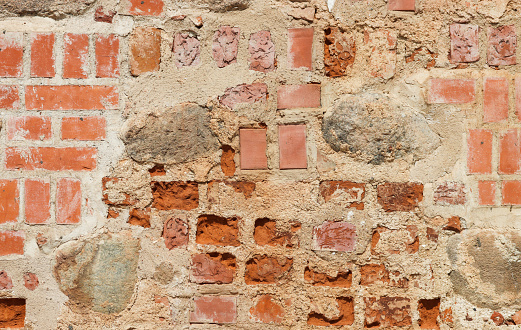 Close-up of an old, abandoned, medieval red brick wall.