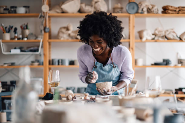 istock Interracial craftswoman is smiling and holding clay work on pottery class 2092499359