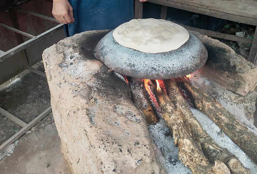 Clay stove with bread is being baked on desi tawa.