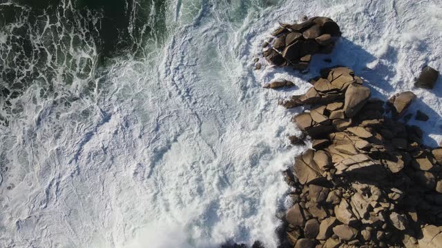 Slow motion top-down view of powerful storm waves rolling onto the rocky shore